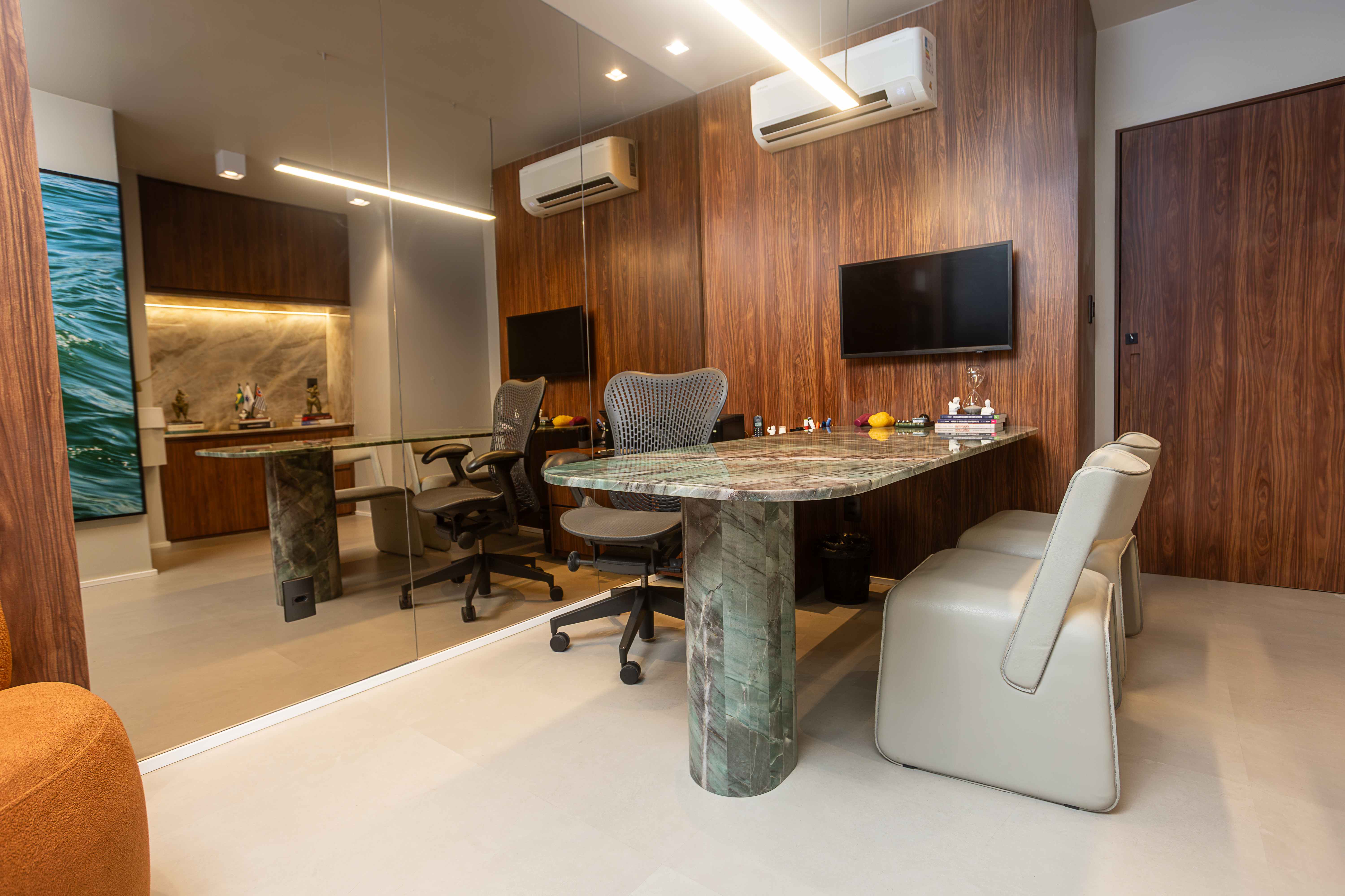 Consultório com mesa de mármore verde e TV