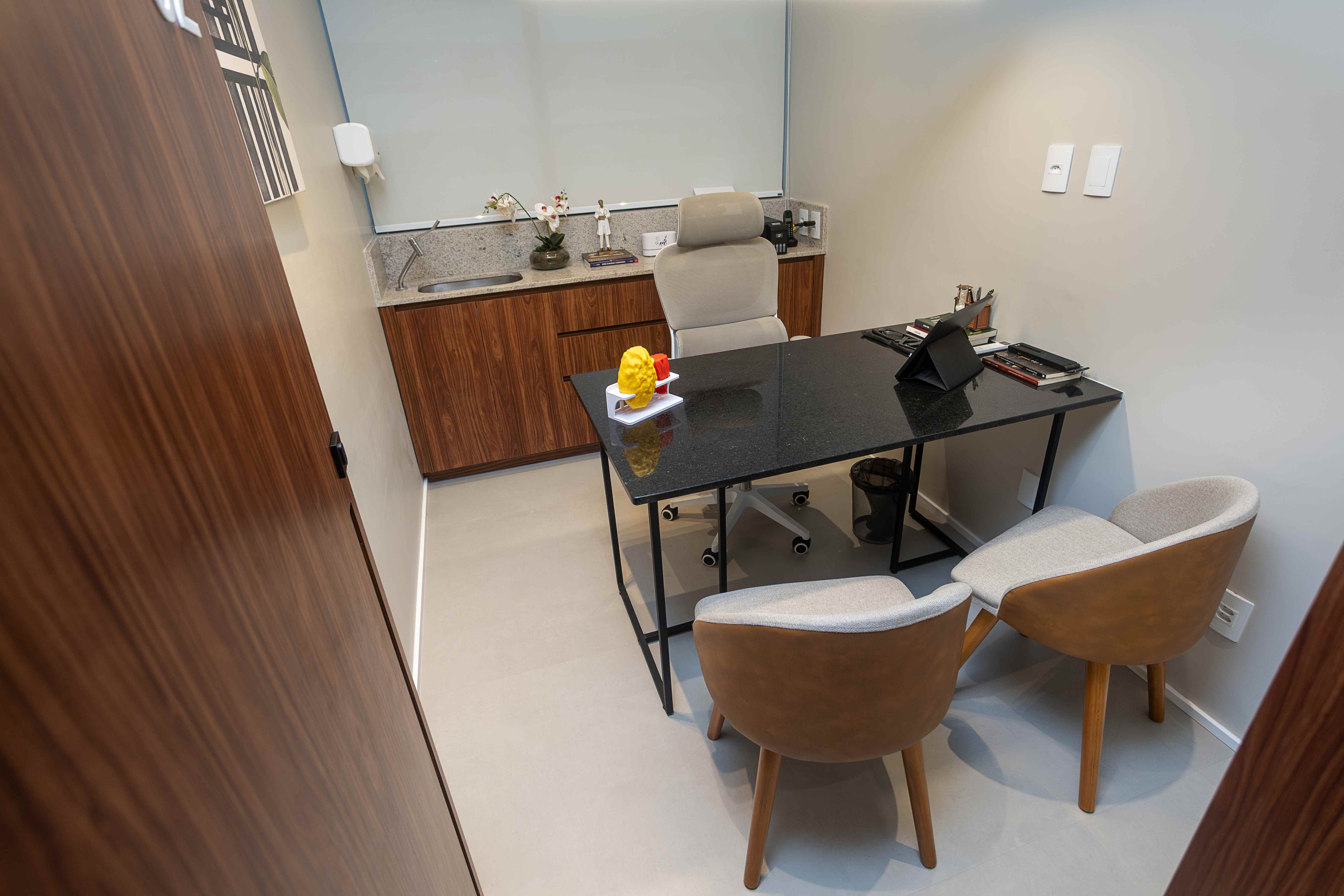 Sala de atendimento com mesa de granito e poltronas